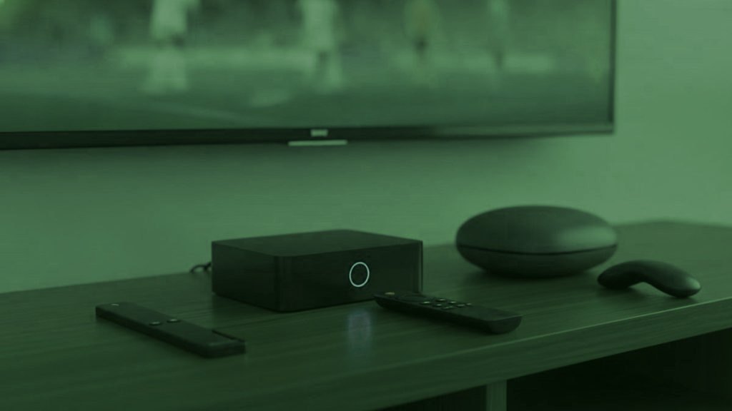 A streaming stick, a set-top box and a round streaming box with their remotes on a TV console