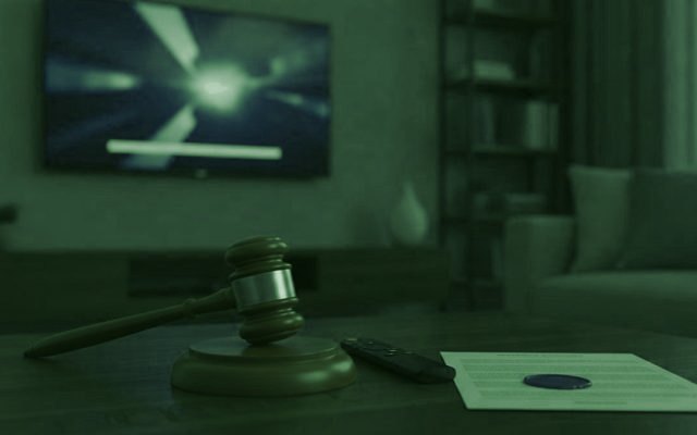 A judge gavel, a streaming remote and a sealed document on a coffee table in front of a TV
